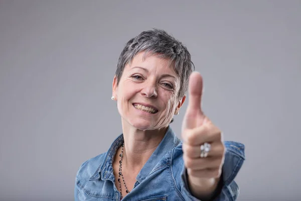 快乐的热情迷人的女士给一个竖起大拇指的手势 以显示她的批准 支持或成功隔离灰色 — 图库照片