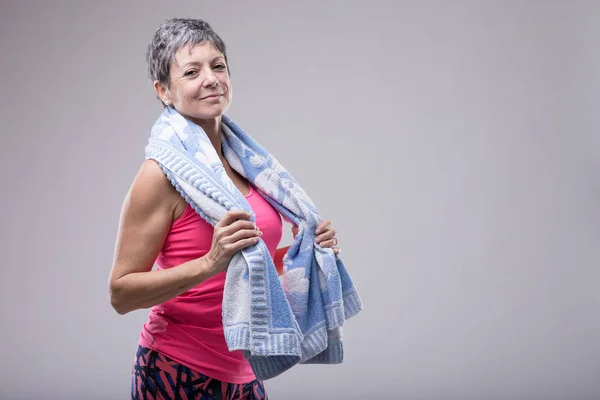 适合有吸引力的妇女与毛巾周围她的脖子后 在健身房工作 微笑着在一个健康和健身概念的相机 — 图库照片