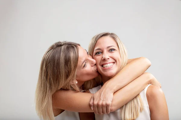 Две Счастливые Девушки Сёстры Целуются Обнимаются Одна Смеётся Над Камерой — стоковое фото