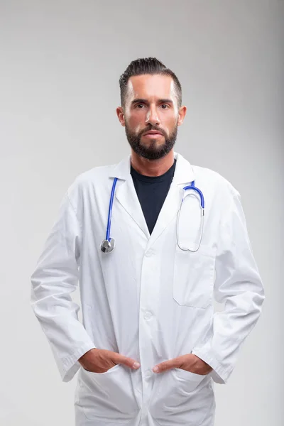 Médico Barbudo Sério Com Mãos Nos Bolsos Seu Jaleco Branco — Fotografia de Stock