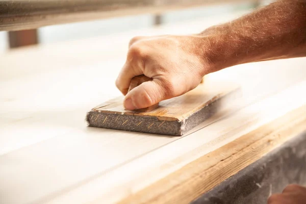 Unidentifiable man sanding large piece of wood — Stock Photo, Image