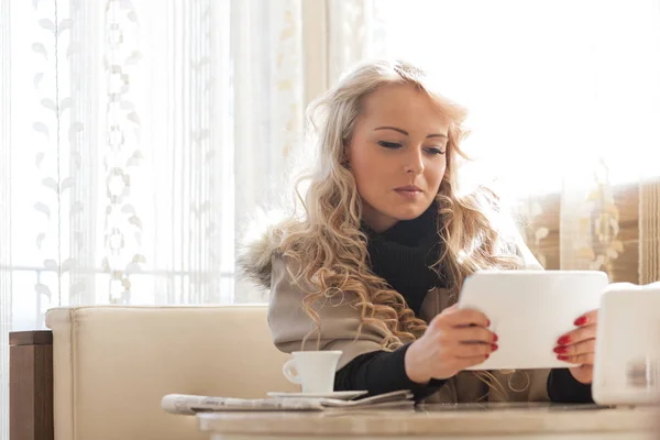 Jonge vrouw lezen op haar tablet over koffie — Stockfoto