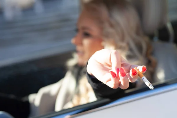 Mujer joven fumando mientras conduce su coche — Foto de Stock