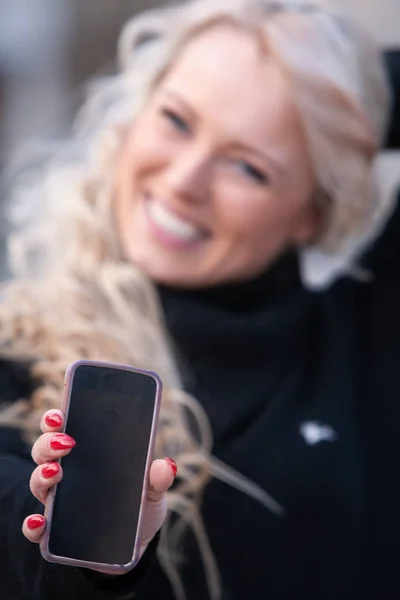 Felice donna ridente tenendo fuori il suo cellulare — Foto Stock