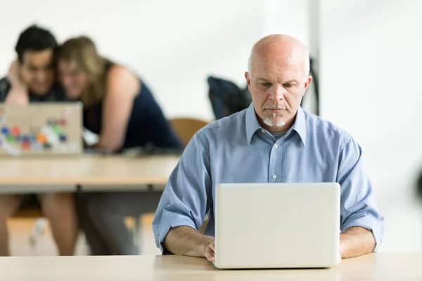 Senior man sitting working on his laptop — Stock Photo, Image