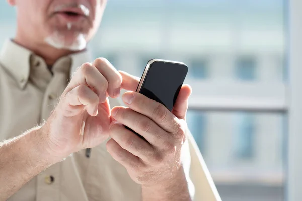 Senior man texting een mobiele telefoon bericht — Stockfoto