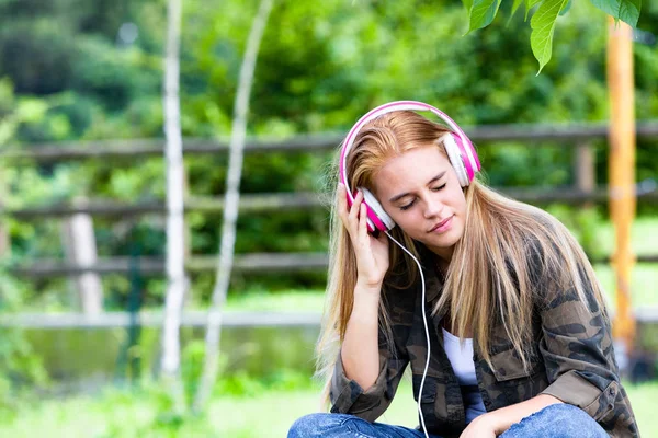 Jovem mulher ouvindo música em fones de ouvido — Fotografia de Stock