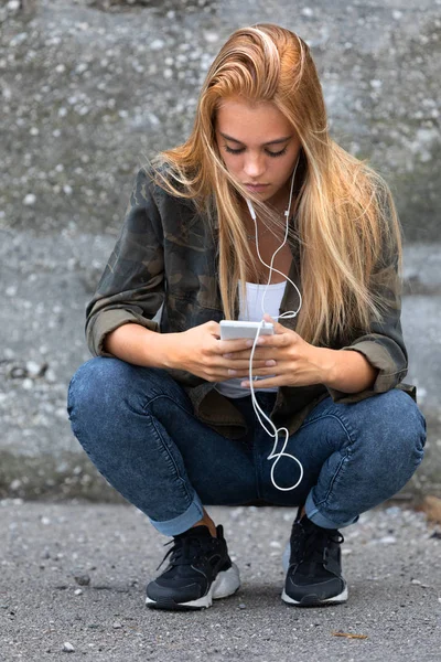 Young woman crouching down listening to music