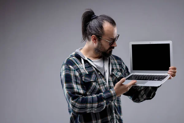 Homme à queue de cheval et lunettes tenant un ordinateur portable — Photo