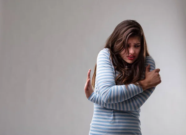 Korkmuş korkulu genç kadın kendini kucaklıyor — Stok fotoğraf