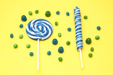 renkli sarmal lolipop ve sarı zemin üzerine şeker çeşitleri