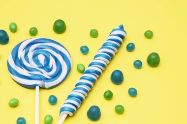 renkli sarmal lolipop ve sarı zemin üzerine şeker çeşitleri