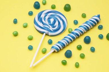 renkli sarmal lolipop ve sarı zemin üzerine şeker çeşitleri