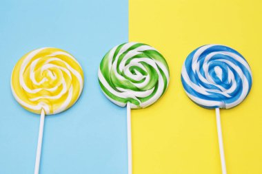 Spiral yuvarlak lolipop sarı ve mavi arka plan üzerinde renkli
