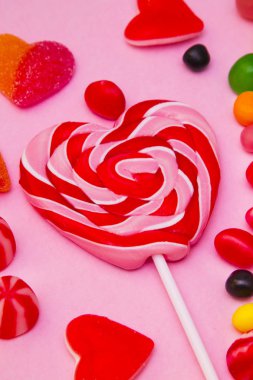 kalp lolipop ve şeker pembe bir arka plan üzerinde