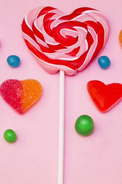 在心脏形状的棒棒糖和粉红色背景的糖果 — 图库照片