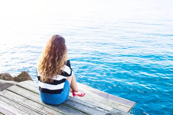 Girl on pier looking at sea