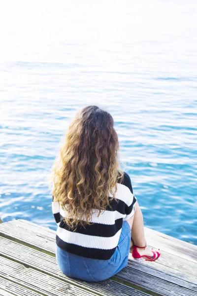 Girl on pier looking at sea