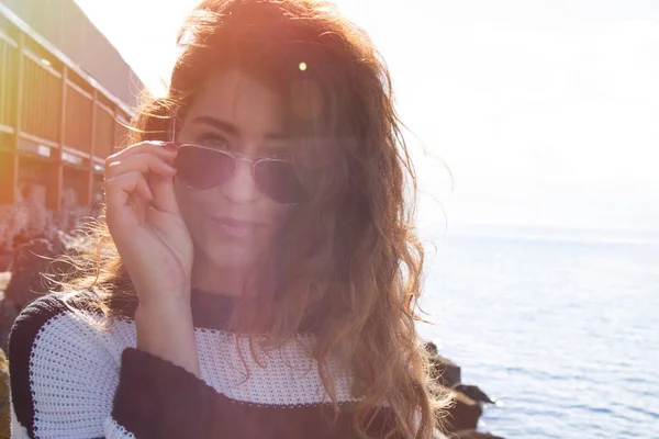 Young woman with sailor jersey and sunglasses with the sea background