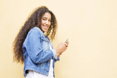 Afrikalı kız cep telefonu ile sarı arka plan kullanarak