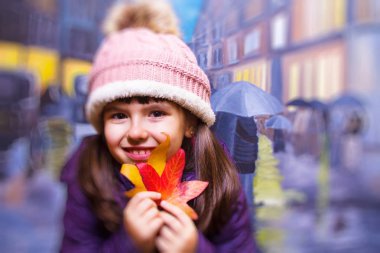 yağmurlu şehir arka plan ile sonbahar ile oynayan kız portresi bırakır