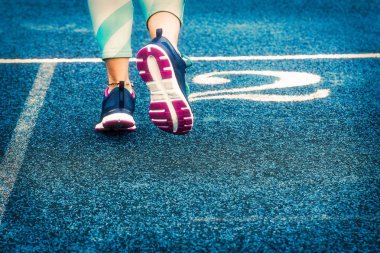 Mavi koşu parkuru üzerinde çalışan beyaz kadın atlet