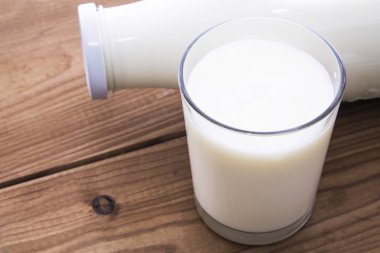 Cam ve ahşap masa üzerinde süt şişesi