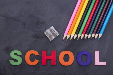 Okula geri dön. siyah tahta üzerinde renkli kalemler, makas ve bileyici