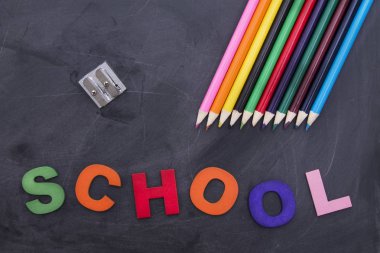 okula geri kavramı, siyah tahta üzerinde renkli kalemler ve sınıf aksesuarları