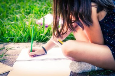 parkta oturan defter ve kalemler ile öğrenci portresi