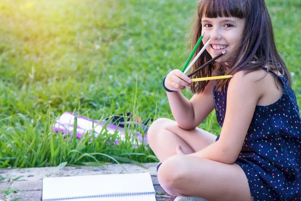 公園に座っているノートと鉛筆を持つ学生の肖像画 — ストック写真
