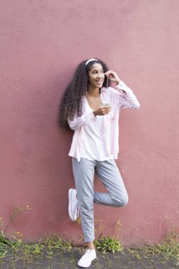 Genç bir kadın cep telefonuyla müzik dinliyor.