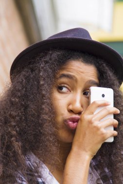 Şapkalı Afro kız cep telefonuna bakıyor