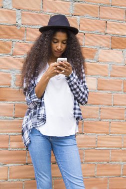 Şapkalı Afro kız cep telefonuna bakıyor