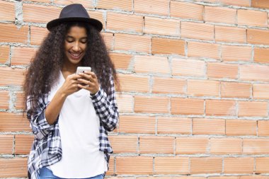 Şapkalı Afro kız cep telefonuna bakıyor