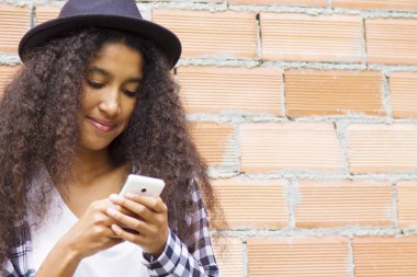 tuğla duvarda cep telefonu ile şapka ile afro kadın