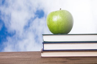 elma ve arka plan üzerinde yığılmış kitaplar ile okula geri kavramı