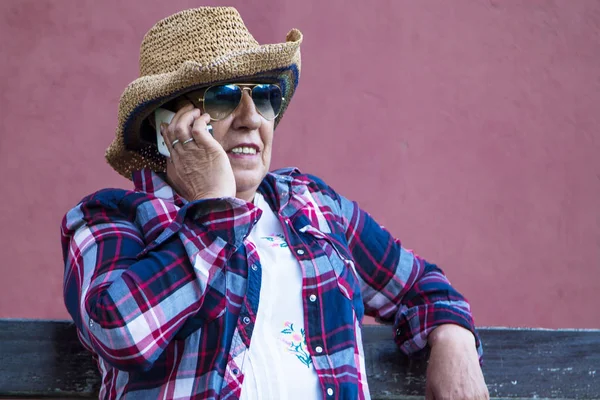携帯電話で話す公園のベンチで先輩女性 — ストック写真