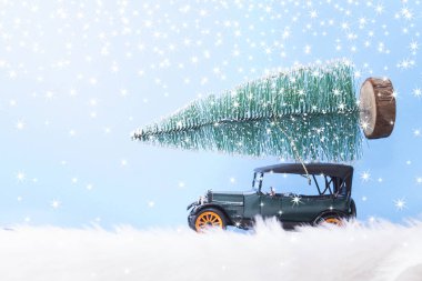 Mavi arka planda Noel ağacı olan yeşil bir araba.