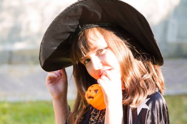 cadılar bayramı partisinde balkabağı ile bir cadı gibi giyinmiş küçük kız