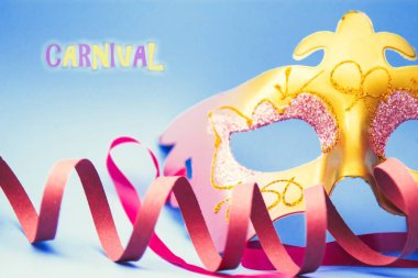 Karnaval maskesi, flamalar ve parlak mavi arka planda konfeti.
