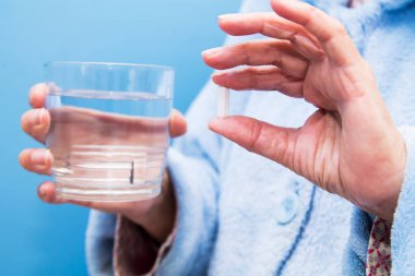 Bir bardak suyla hap alan yaşlı bir kadın, ilaç ve sağlık konsepti