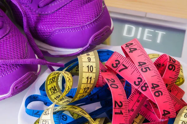 scales, sport shoes and colored measuring tape, concept of diet and health