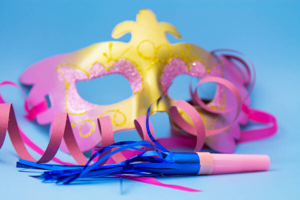 Карнавальная маска, ленты и конфетти на ярко-голубом фоне
