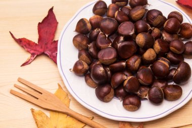 Tahta arka planda kestane tabağı ve yapraklar