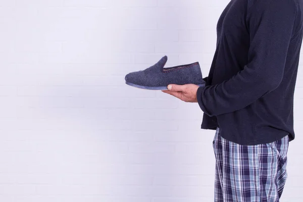 man in pajamas holding house slippers