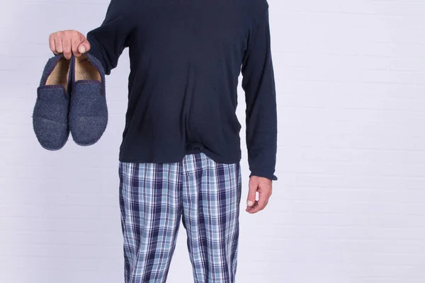 パジャマを着た男が家のスリッパを持って — ストック写真
