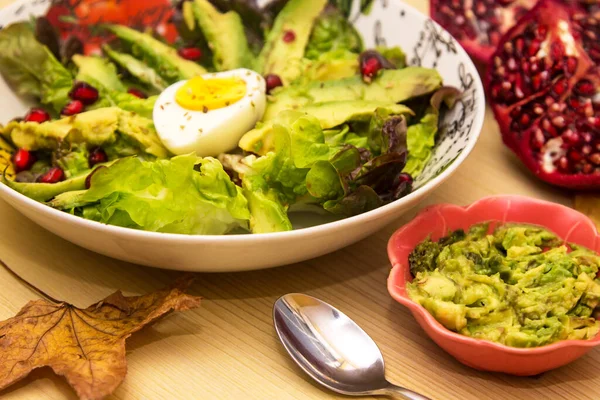 Avocado, egg and pomegranate salad with guacamole, diet and food concept