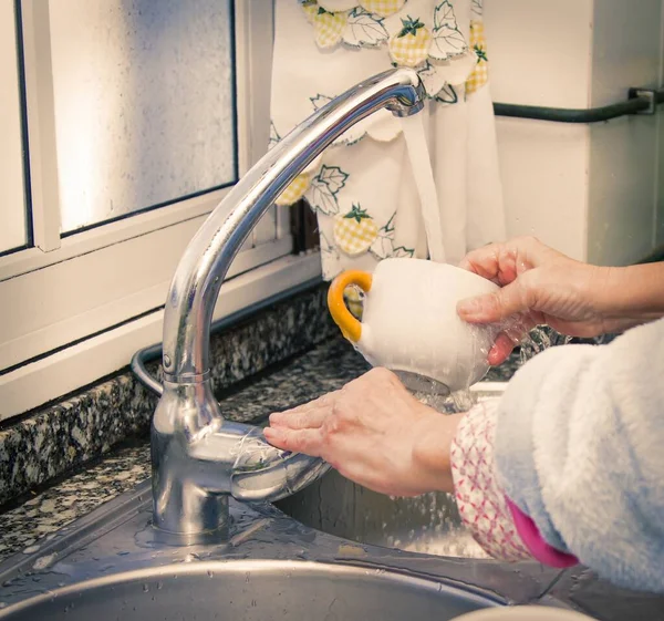 woman putting detergent in the scourer, to wash the dishes