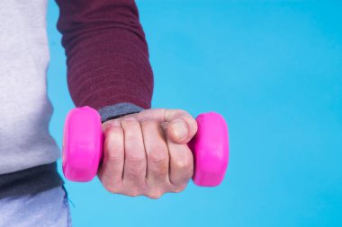 Adam mavi arka planda dambıl yapıyor.